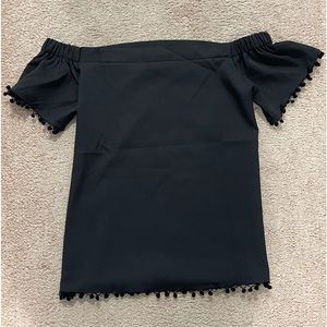 Super cute off the shoulder top w/ little pom poms on the bottom and shoulders.